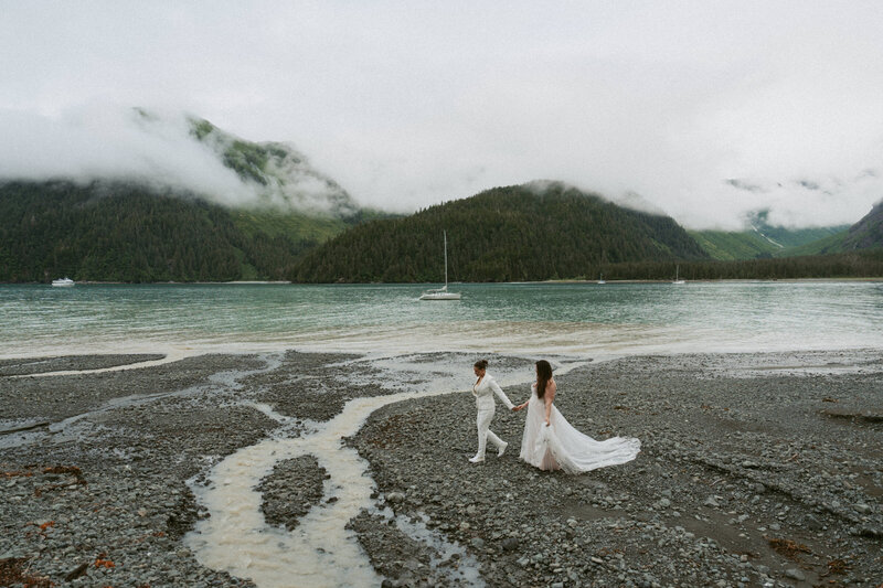 Two brides walking hand in hand along the coast near Seward, Alaska.