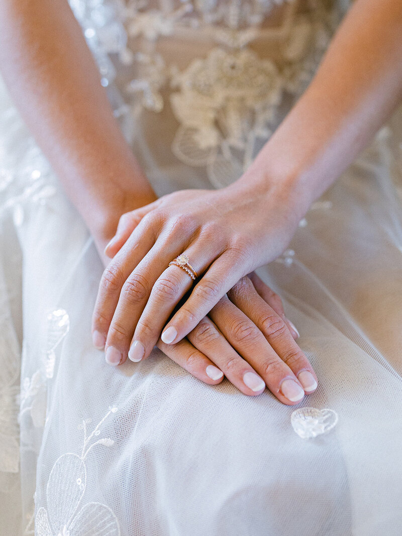 the hands of the bride on her wedding gown with her wedding rings