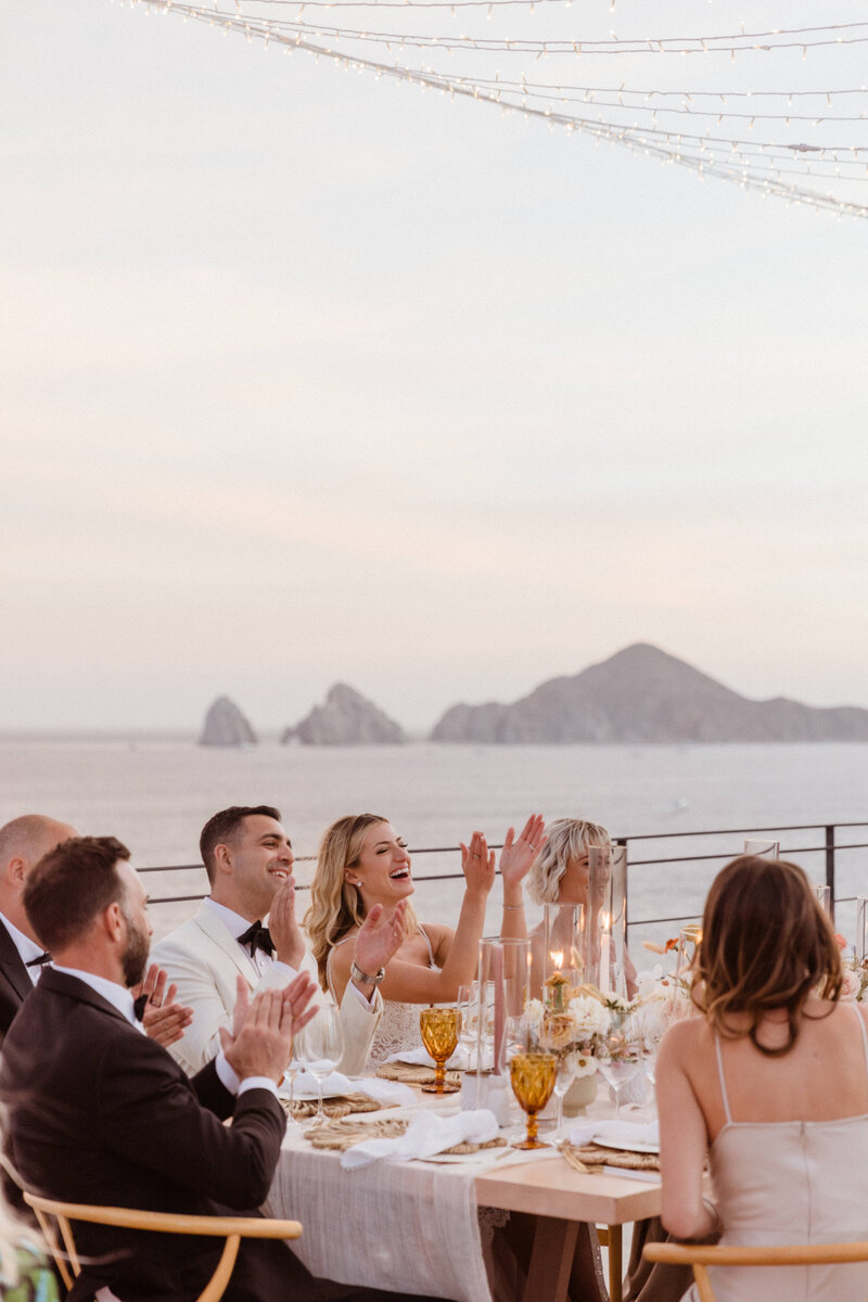 bride and groom sitting at table with bridal party