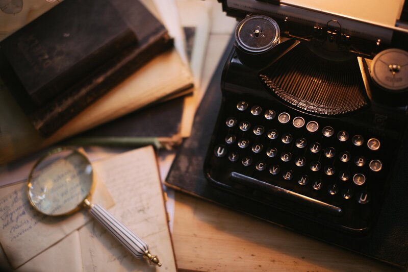 Vintage desk setup with an old typewriter, editing papers, and magnifying glass, representing traditional copy editing and proofreading services.