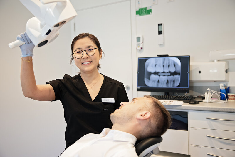 Dentist moving light above happy patient