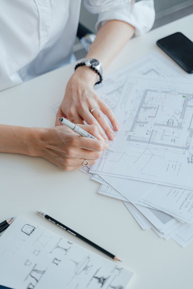 Woman in white shirt marking up plans for interior design changes