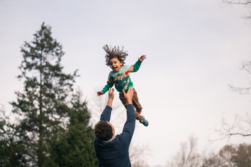 dad tossing son in the air during a boston family photo shoot
