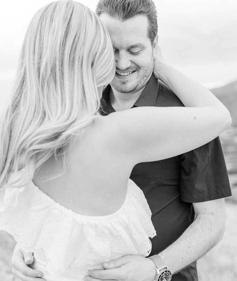 Man smiling holding a woman during their engagement session at Mesa Overlook near Garden of the Gods.