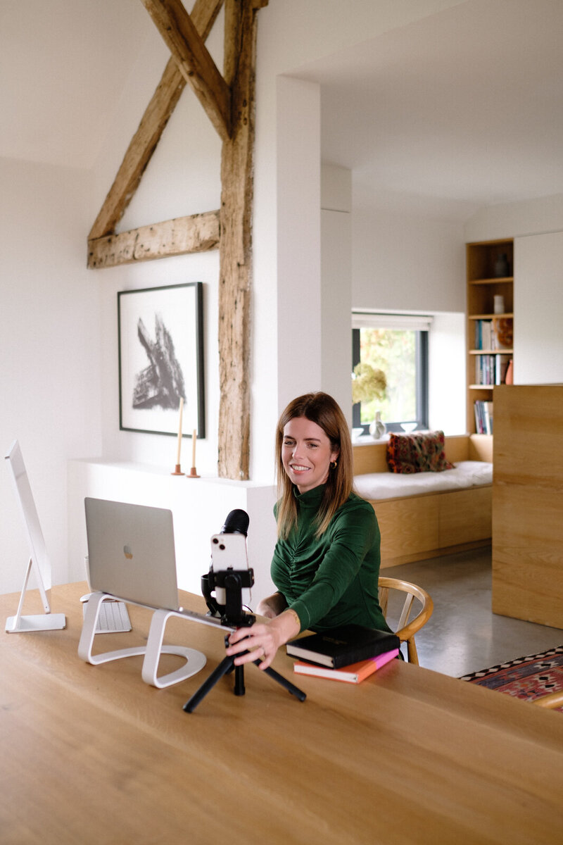 A woman sitting at a desk, focused on her work with a laptop and microphone in front of her.