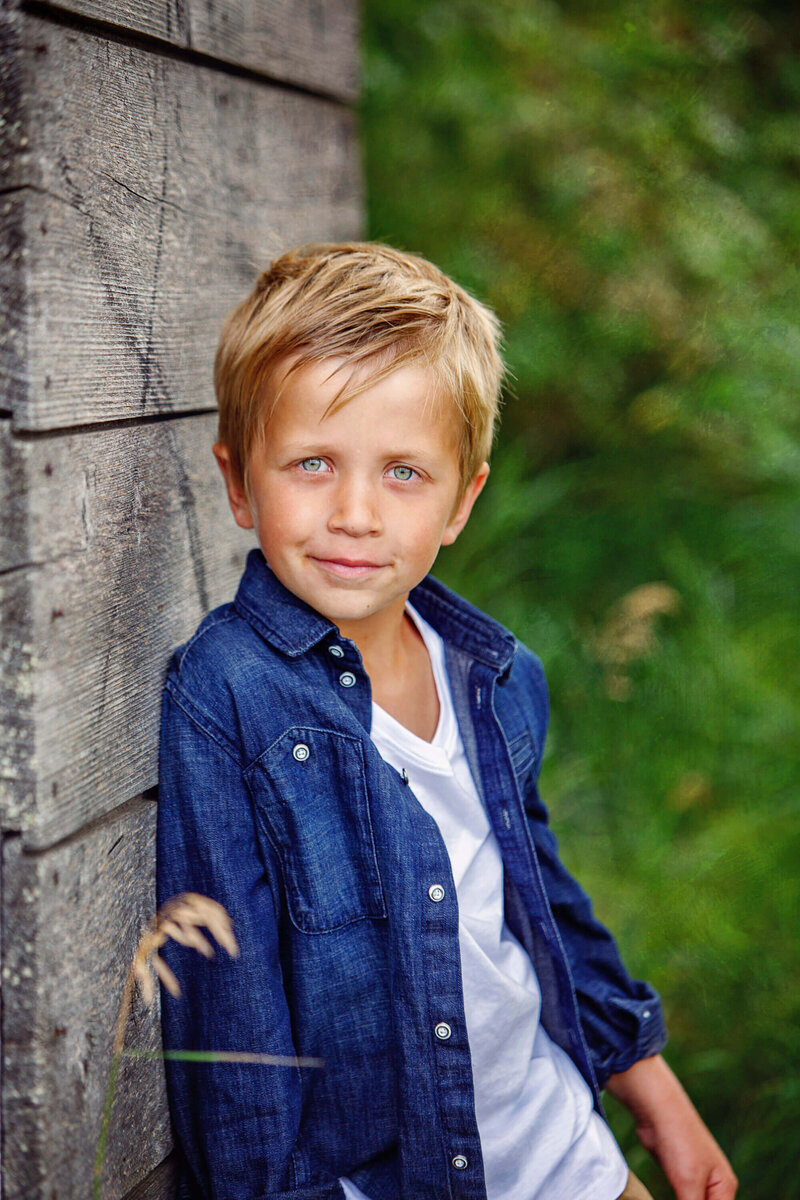 little boy leaning on shed