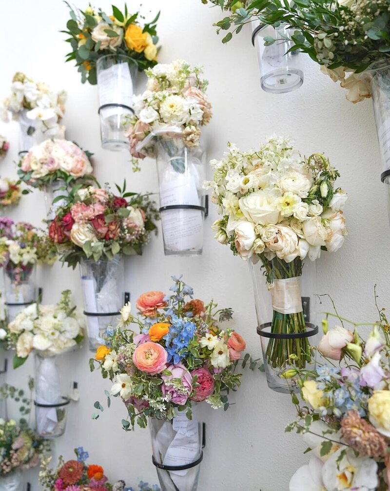 A wall of bridal bouquets waiting preservation by Pressed Floral