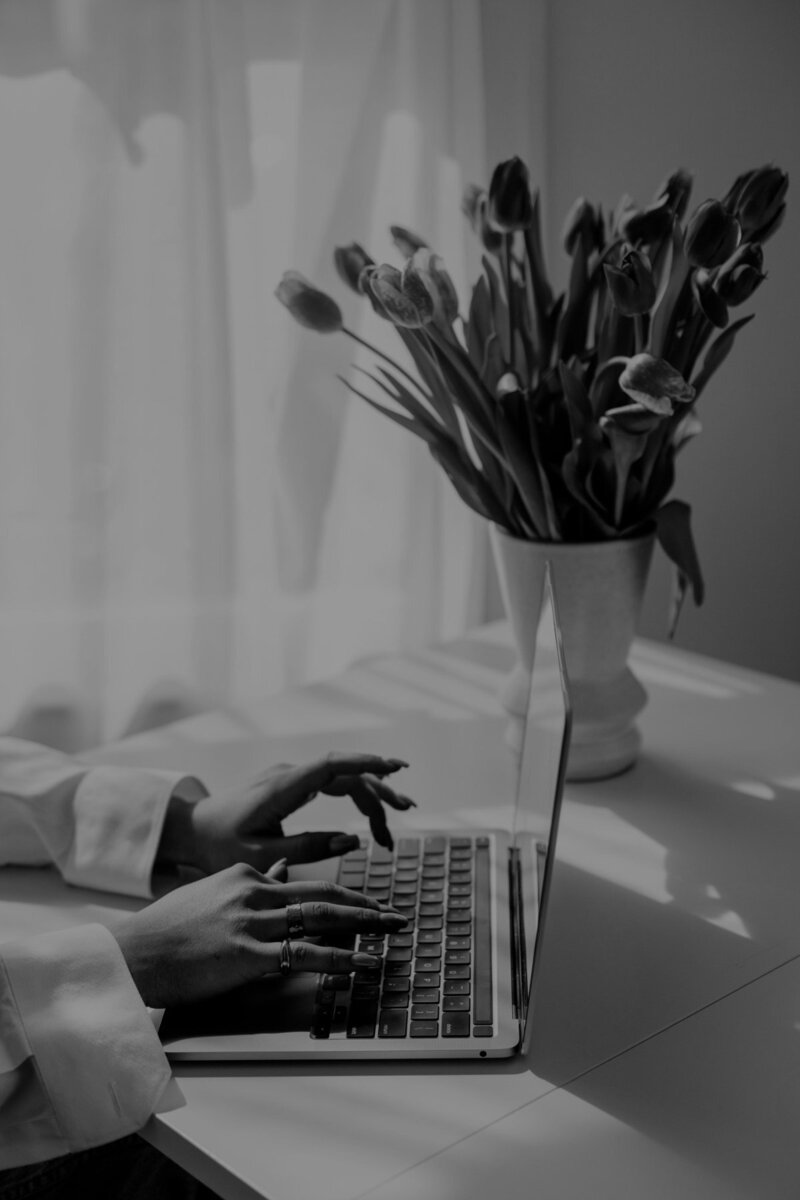 Background image of a workspace with laptop, water glass, and flowers used in the Aurum Design Studio menu
