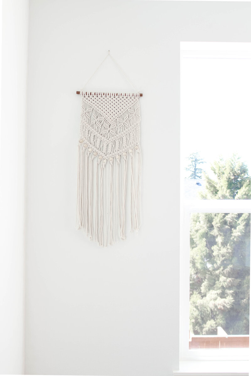 white wall with large window, woven white hanging tapestry