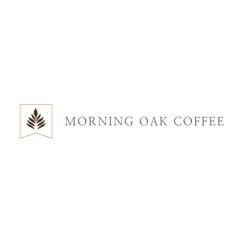 Logo for Morning Oak Coffee with a stylized oak leaf symbol in brown inside a square banner outline. The words "MORNING OAK COFFEE" appear in simple serif font to the right.