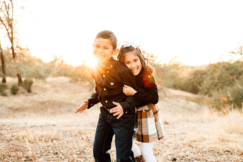 Backlit image of siblings embracing