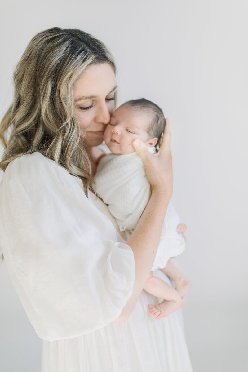 Mother holding newborn baby in clean studio setting