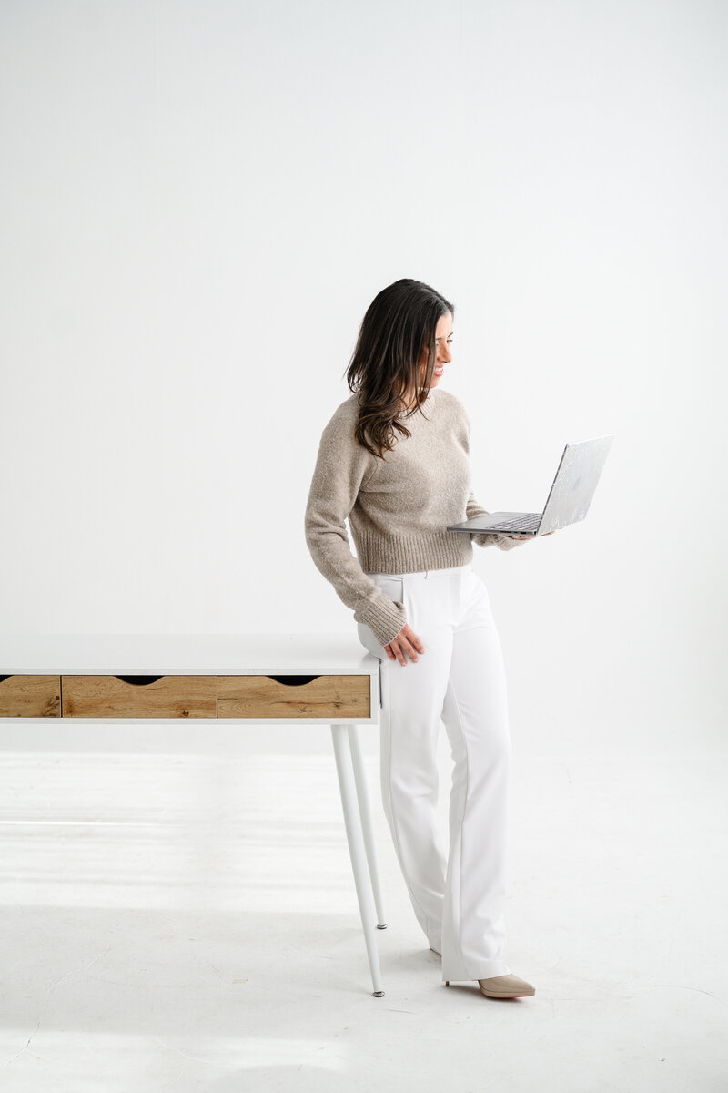 Jo, founder of Branding by Jo, sits with a laptop on a  studio in Orlando, highlighting her professionalism and branding expertise.
