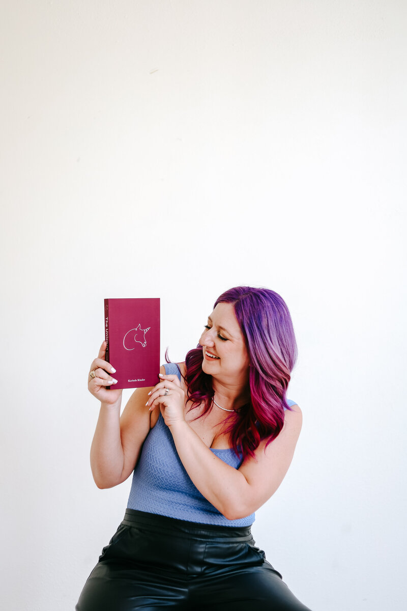 Photography Business Coach | Karinda K | Karinda holding her Unicorn Book for Photographers