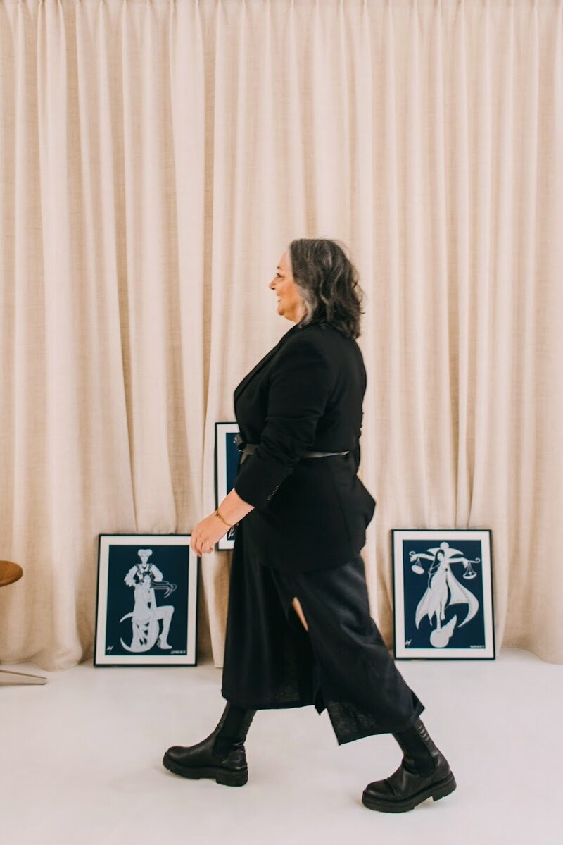 Astrocartographer Kristine Odegard walking in her office with zodiac posters