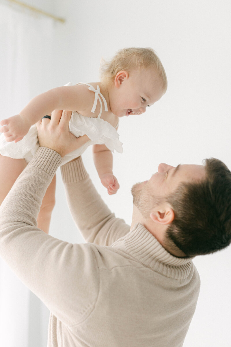 knoxville tennessee newborn photographer dad holding smiling baby girl in the air