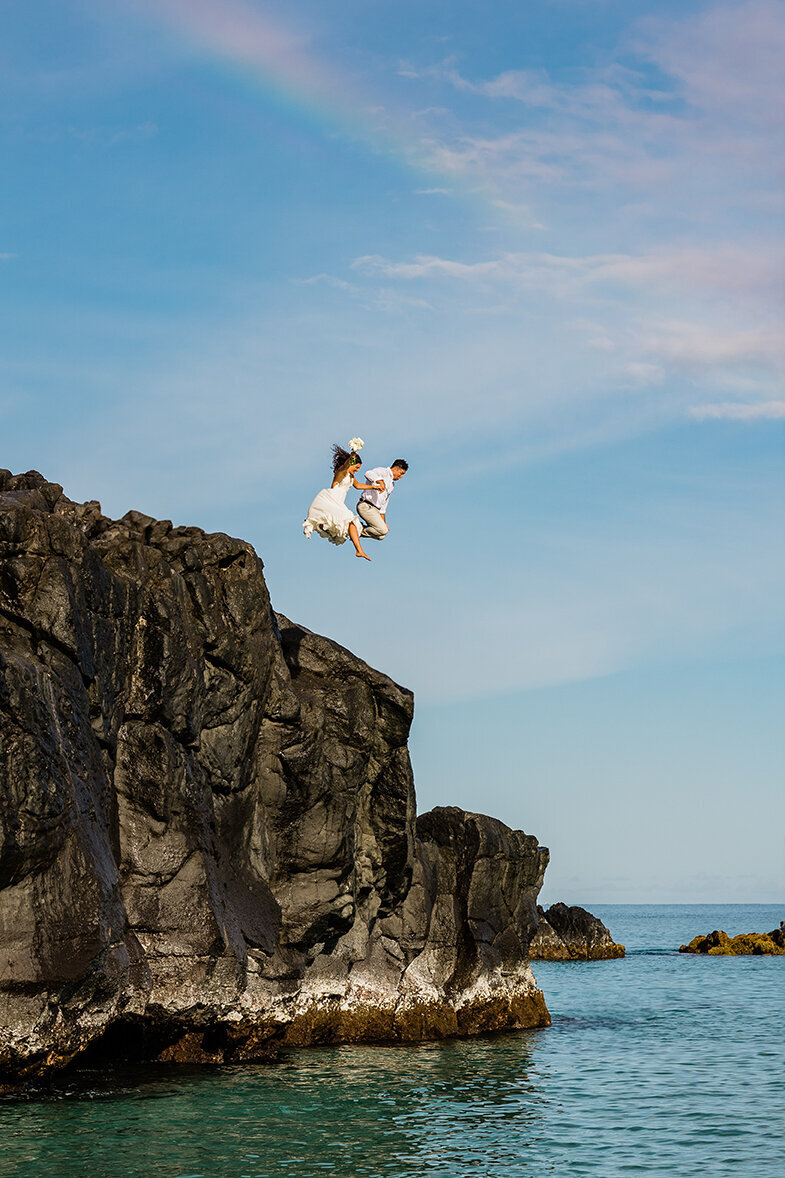 oahu elopement at Waimea Bay. Bride and groom jumping off cliff into the ocean.