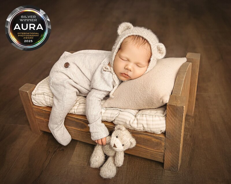 newborn photos in OKC. Award winning photo of newborn on small bed with bear ears.
