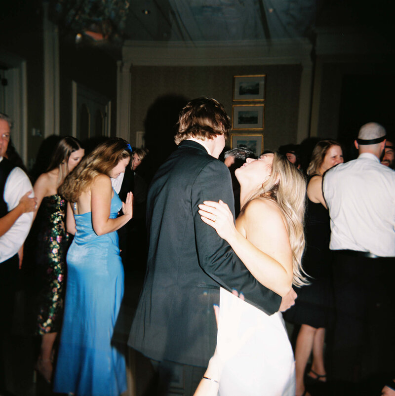 Candid image of a married couple dancing together during their wedding reception with the bride in her second dress