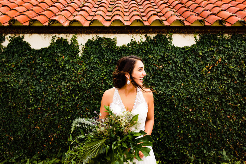 A bride laughing while standing in front of a vine covered wall at the Catawba Island club in Ohio