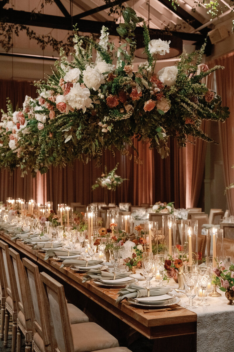 Ornate white chairs are arranged in rows on the grass outdoors with flowers in shades of purple and white