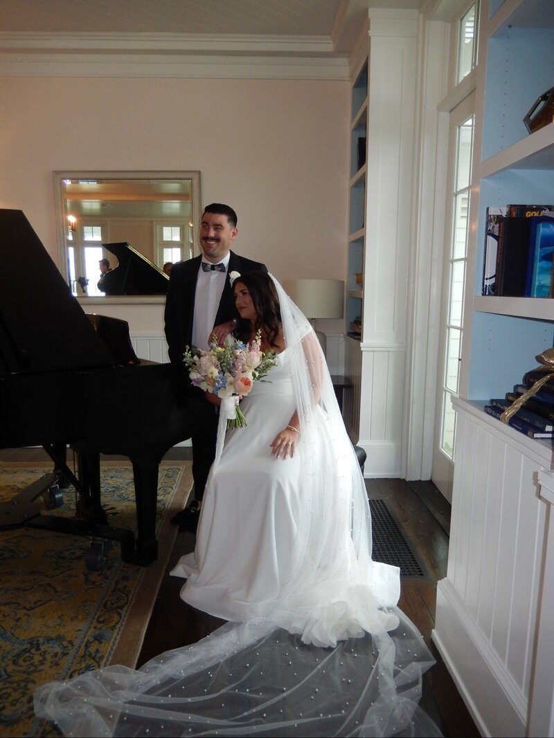 Meg and her groom sitting at a piano together