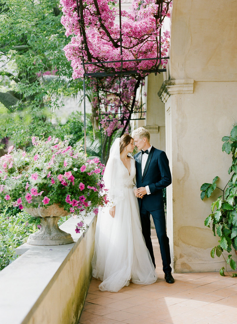 bride and groom on balcony with flowers in positano, italy