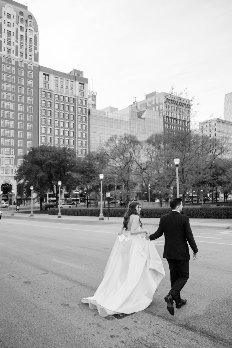 Elegant bride and groom walking hand in hand outside the historic Blackstone Hotel, captured by Chicago wedding planner Savoir Fête. The stunning Chicago skyline and iconic architecture provide a picturesque backdrop for their special day.