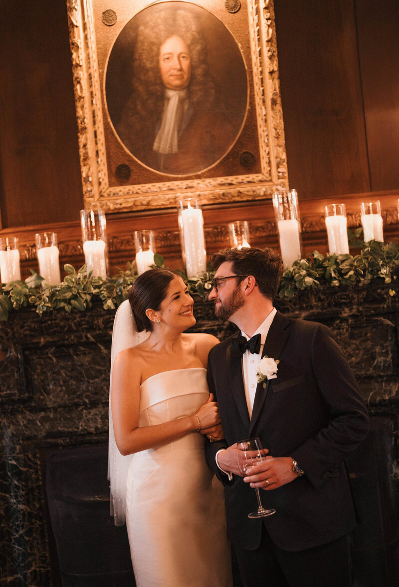 Bride and groom smiling at each other over candlelight.
