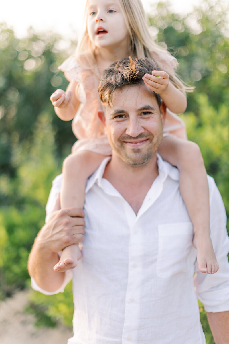 Young girl rides on her dad's shoulders