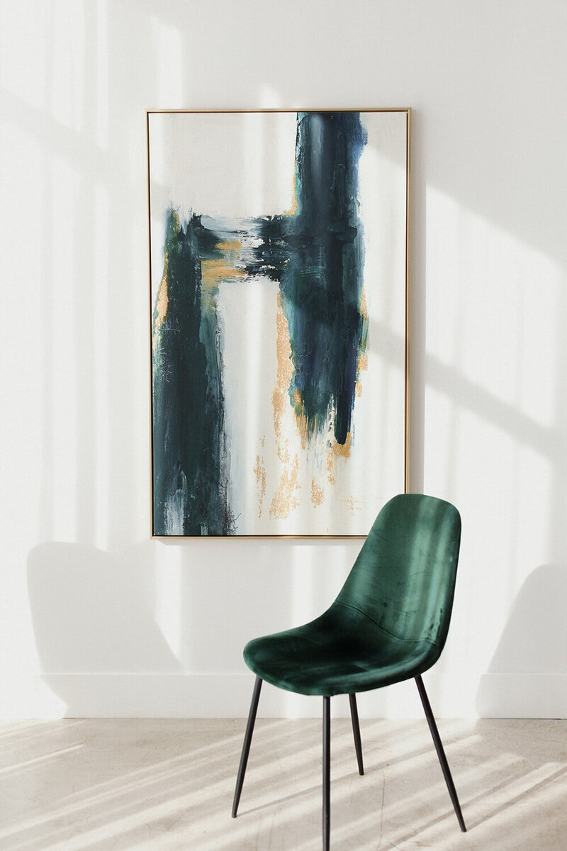 A green chair, and elegant painting hanged to the wall