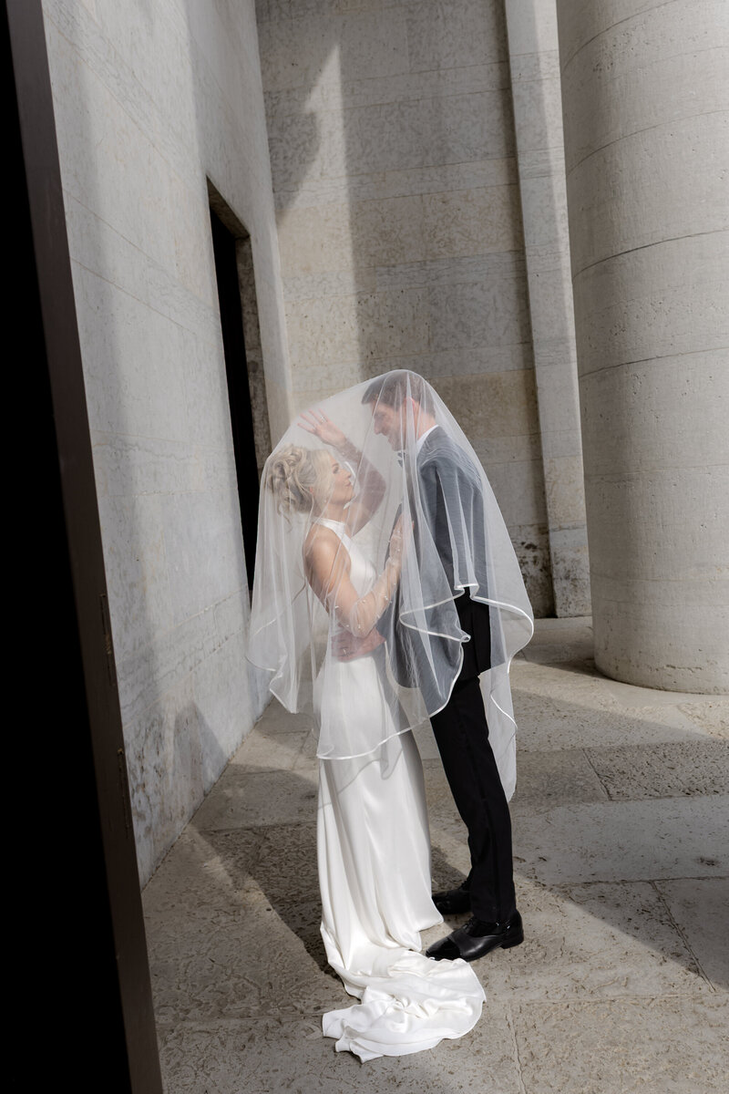Bride and groom under veil on their wedding day in Columbus Ohio photographed in a modern editorial documentary style.