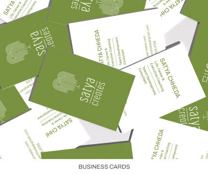 Stacks of green and white business cards that say Satya Creates