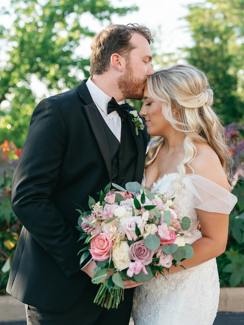 Groom kissing his bride's forehead