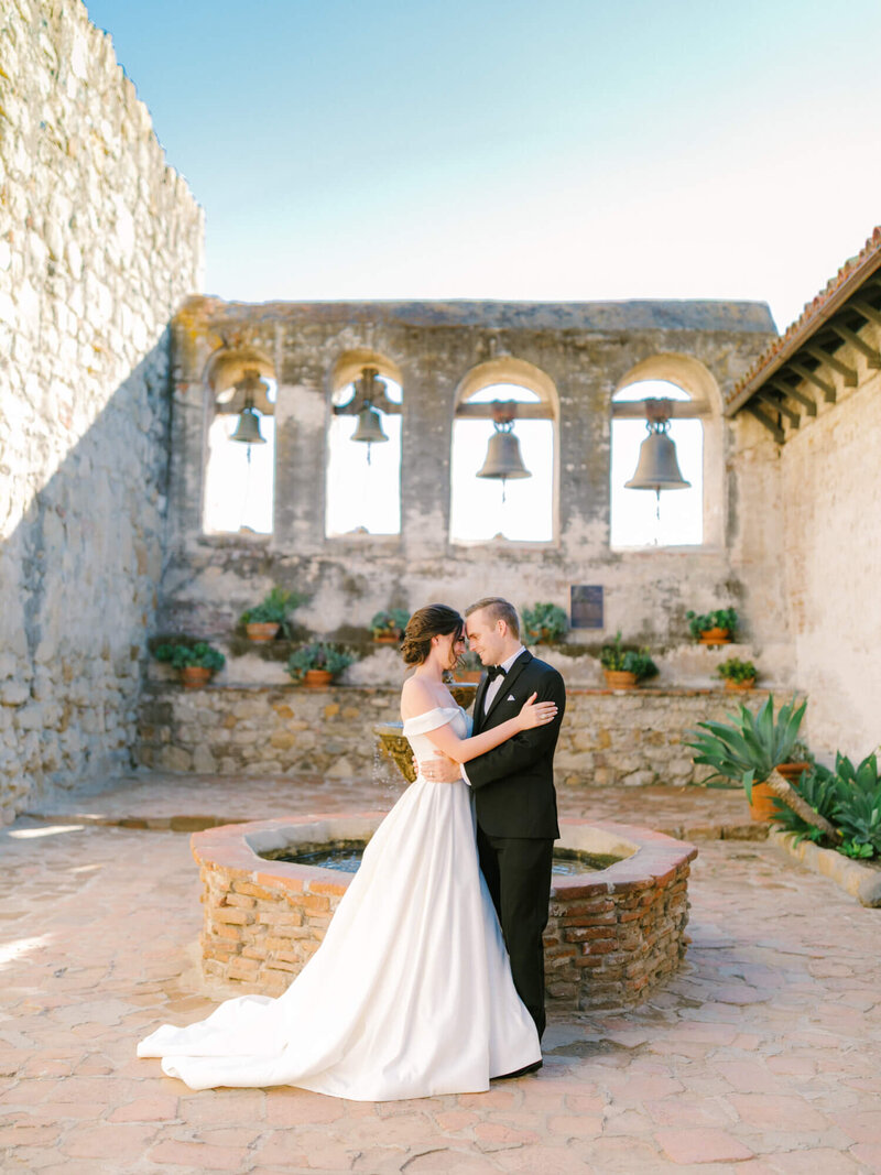 bride and groom wedding photography at mission san juan capistrano with the bells in the background