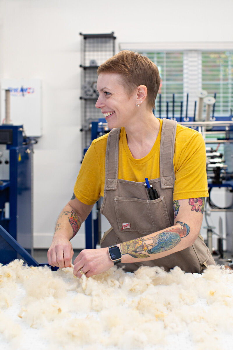 an image of a wool entrepreneur in her mill, smiling at someone.