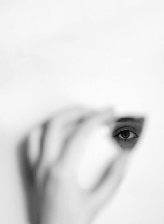 A black-and-white image of a person's eye seen through a small fragment of a mirror, symbolizing self-reflection, introspection, and inner clarity.