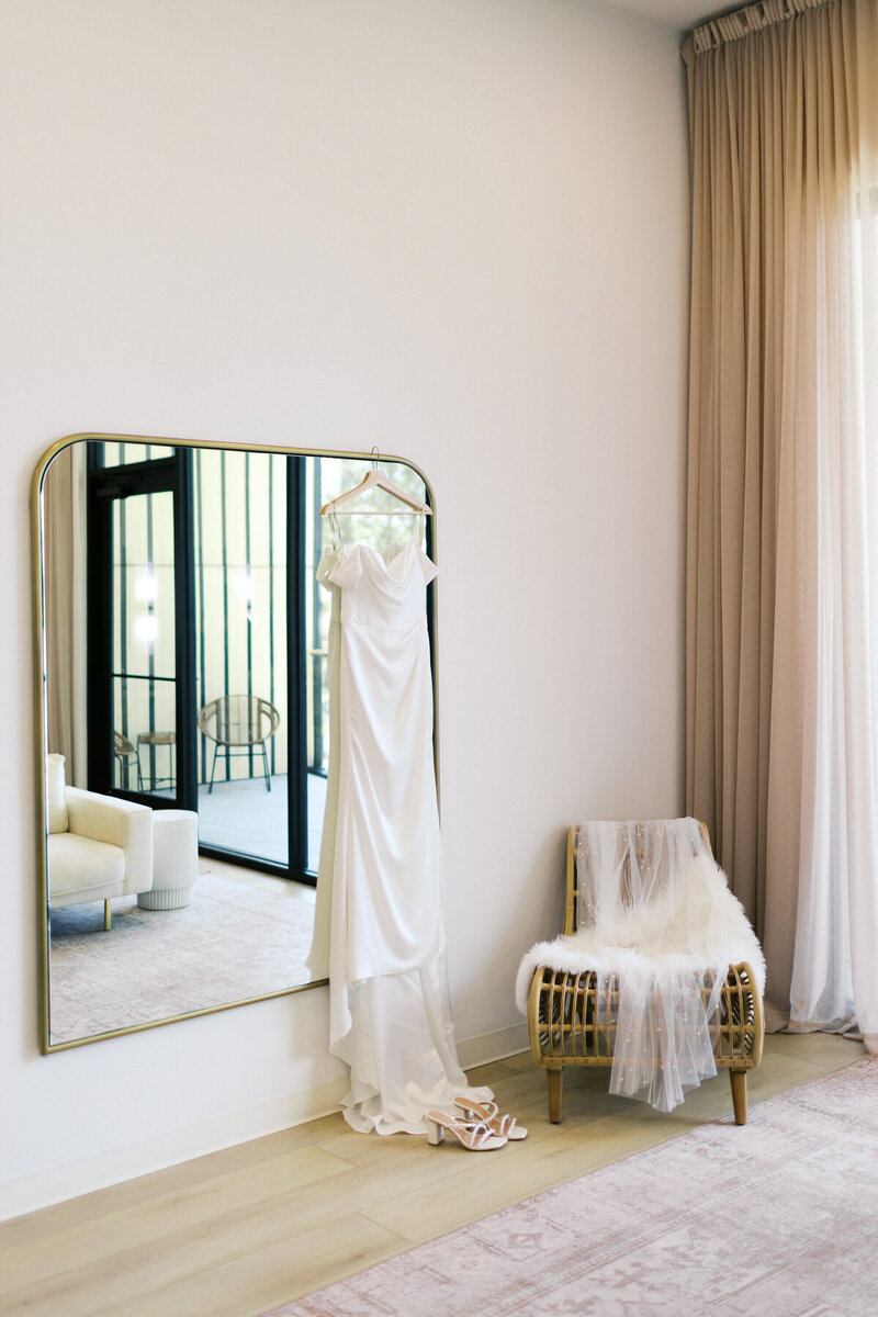 Wedding dress hanging on the wall with wedding shoes standing next to it at Catalyst by NatureLink wedding, captured by Minnesota wedding photographer.