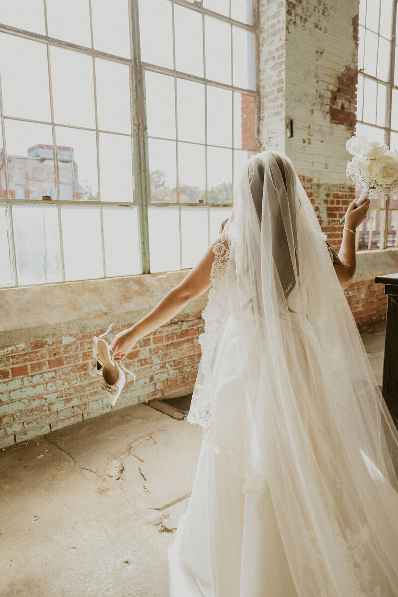 Latina bride after wedding ceremony holding her shoes and bouquet Photo Simplamor