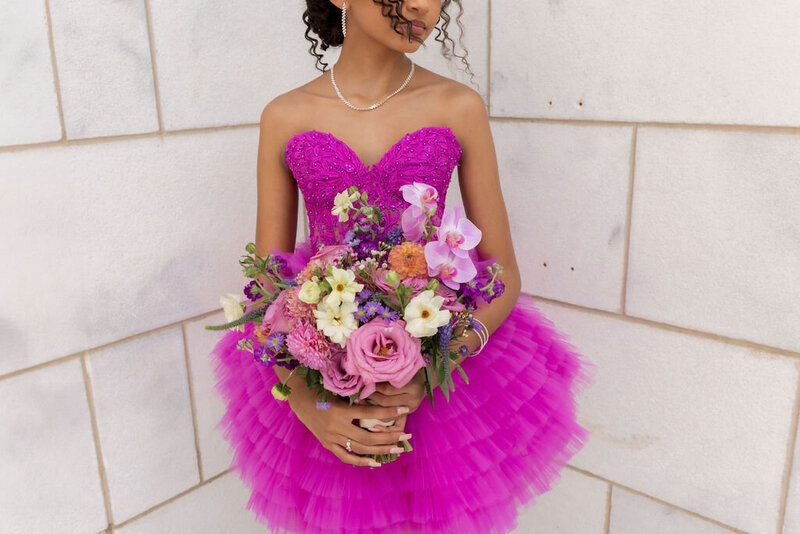 woman in quinceanera dress standing in front of large stone building