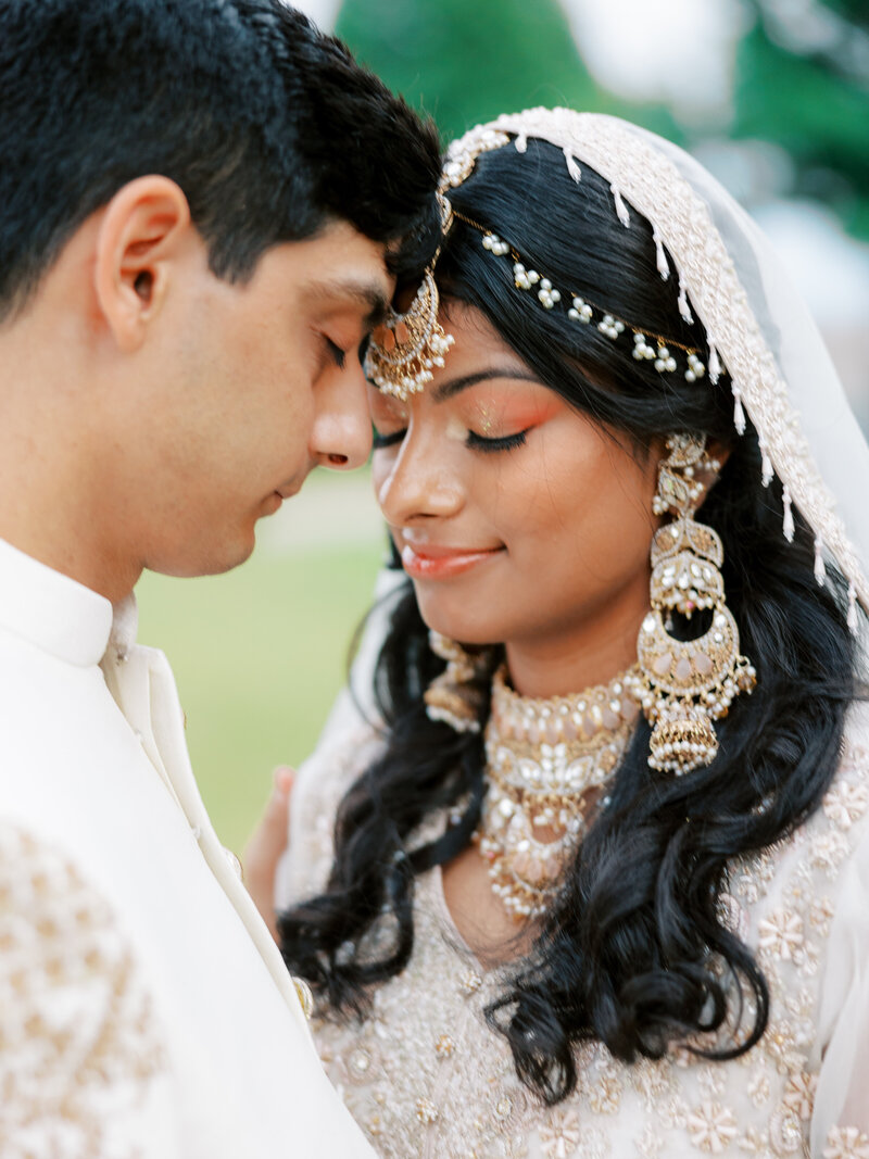 Bride and Groom in Nikkah attire for Indian wedding pose together with eyes closed at Clinton Library in Little Rock, Arkansas