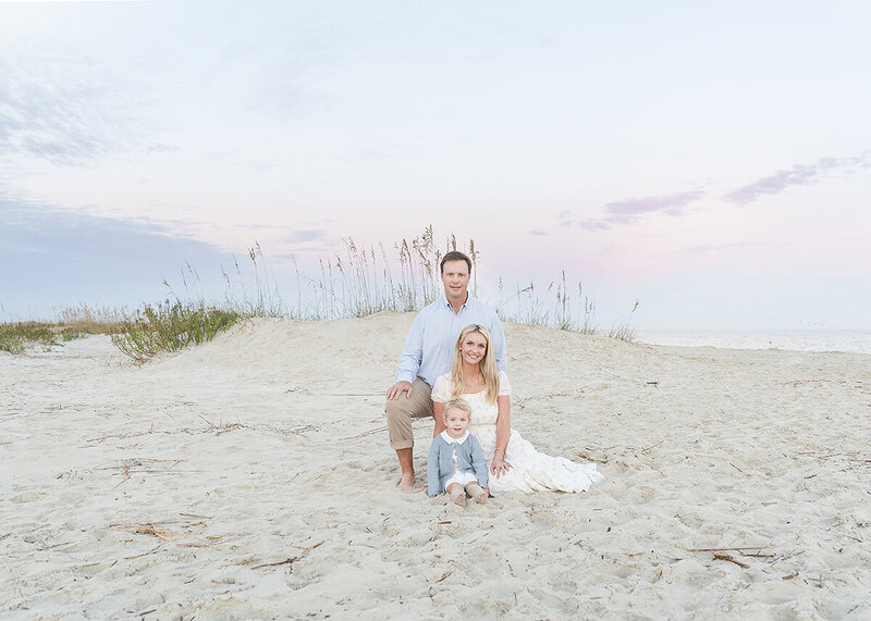 black and white picture of a baby gently held in mom and dads hands