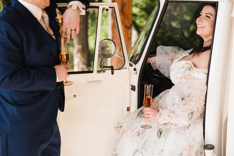 Bride sitting in a small truck sharing a sip of prosecco with the groom