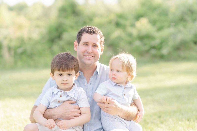 Dad smiling with sons during photography in Prince William County, Virginia