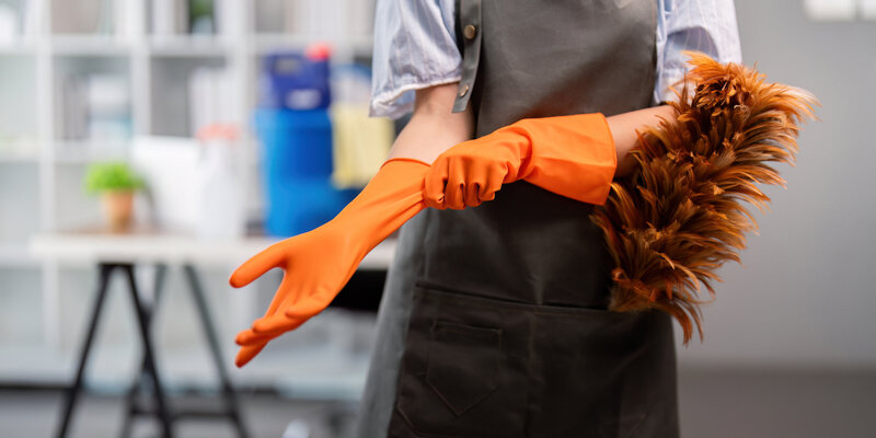 vecteezy_female-office-cleaner-putting-on-gloves-with-duster-concept_46414728