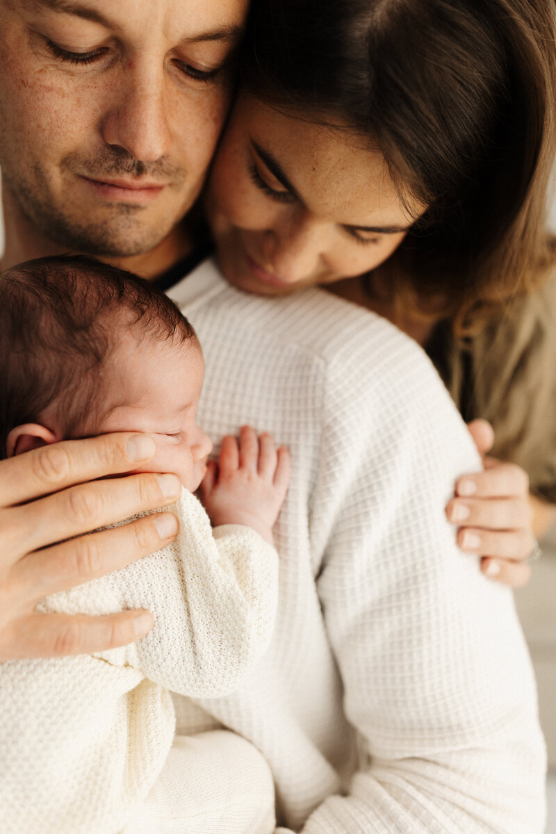A mother and father holding their newborn during their studio newborn photoshoot with Christchurch photographer Lucy Jane Photography