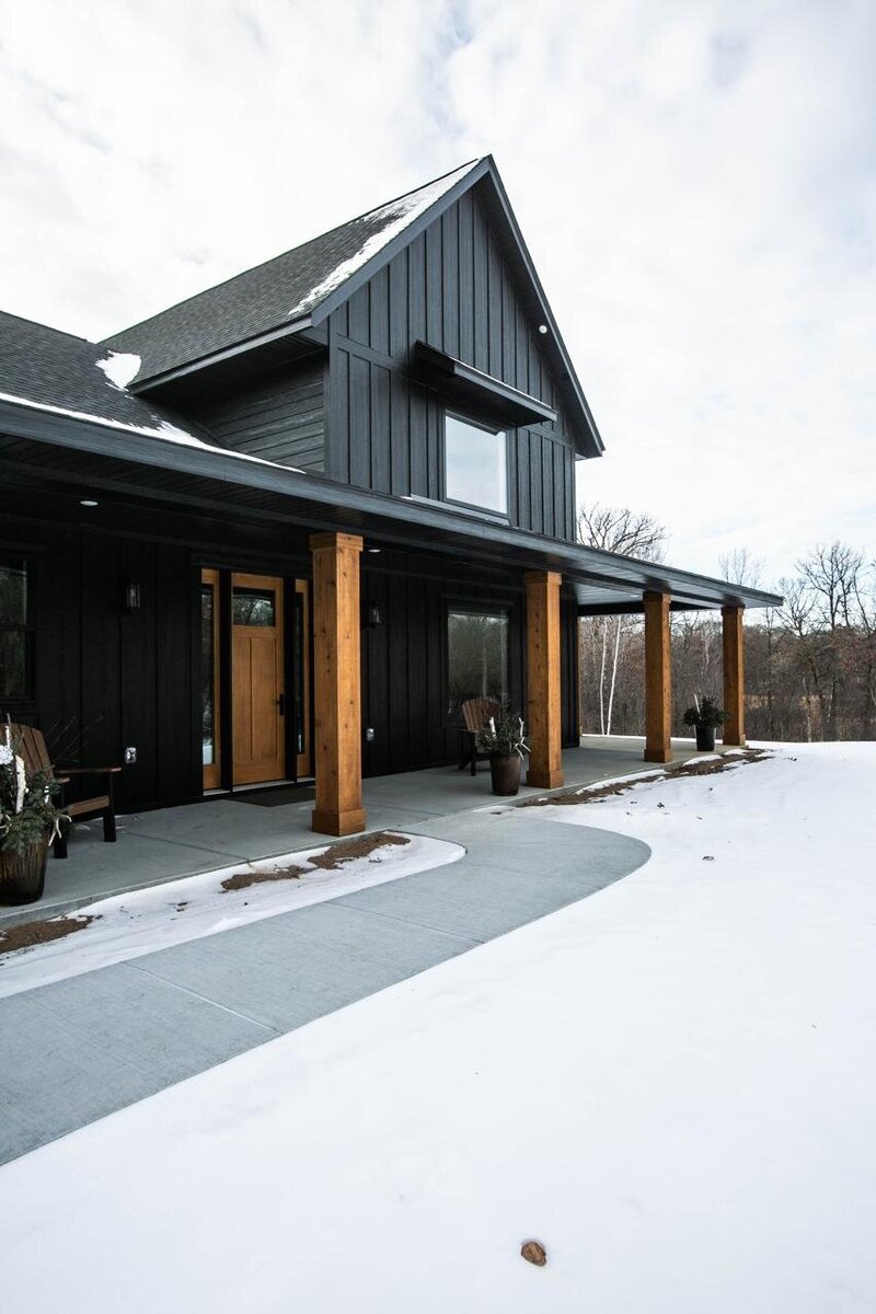 Custom Minnesota Home built by Cornerstone Custom Builds with black siding and wood pillars.