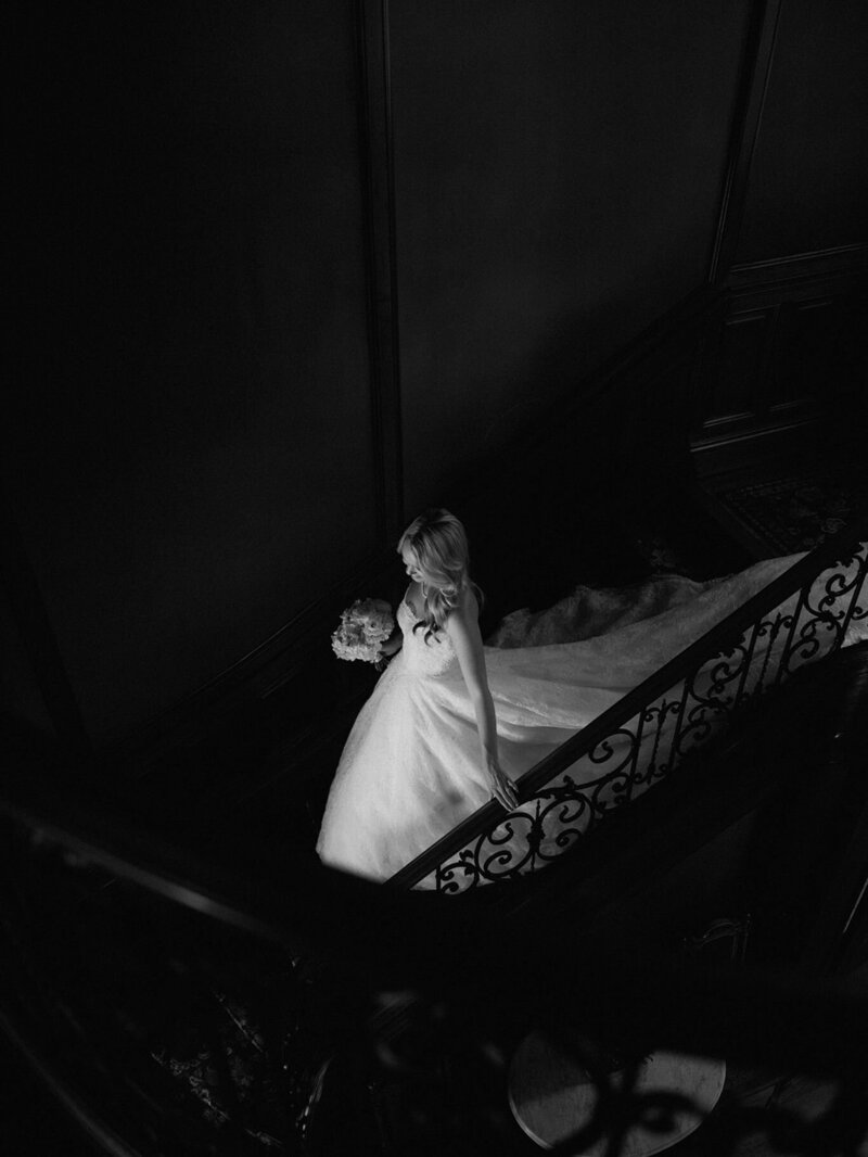Bride kneeling beside a flower girl, sharing a sweet moment by the window before the ceremony.