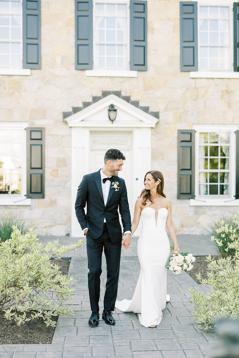 Couple holds hands and smiles outside of Barn at Silverstone wedding venue in Lancaster, PA