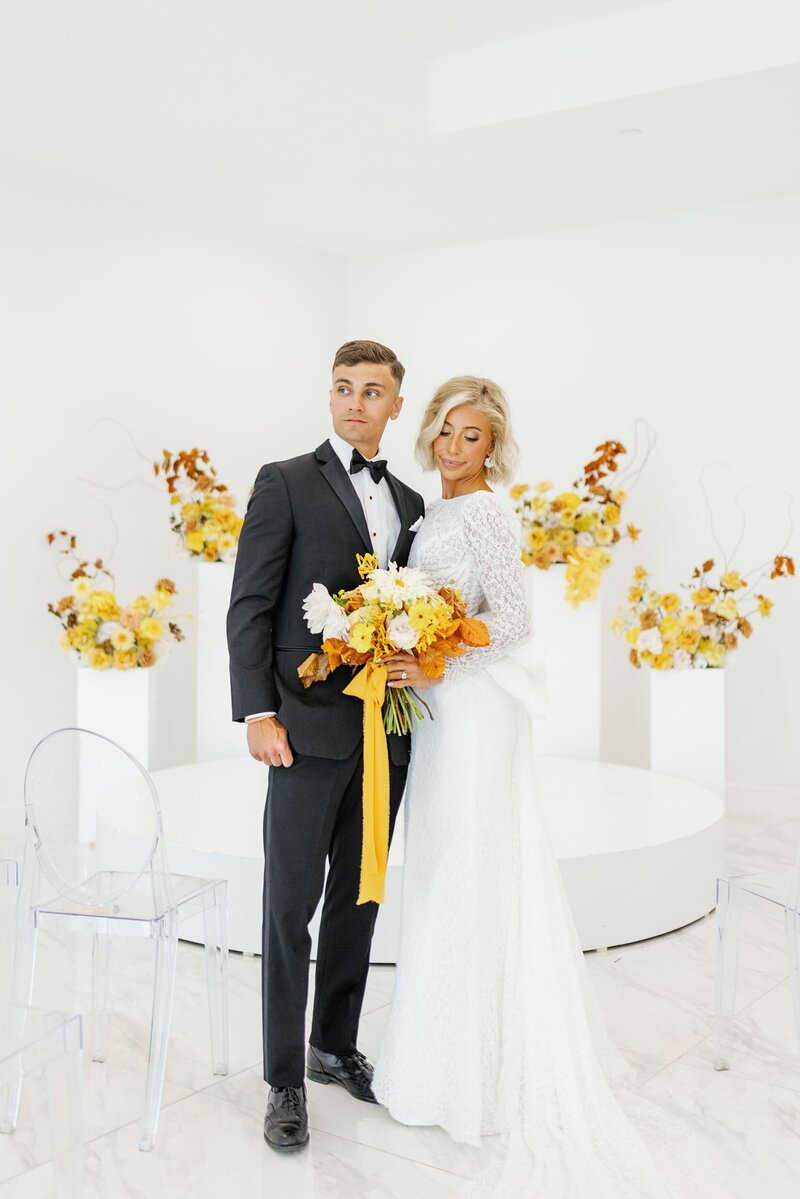Bride and groom white venue with orange and yellow florals